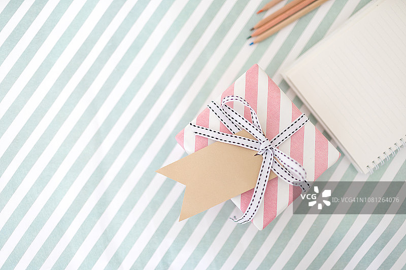 女人手在床上拿着带礼品标签的礼品盒图片素材