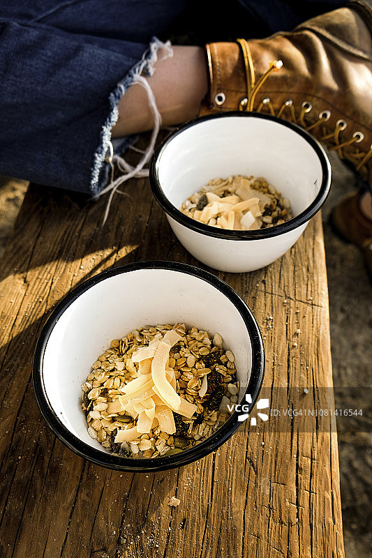 在木桌上的碗里放早餐谷物的年轻女子图片素材