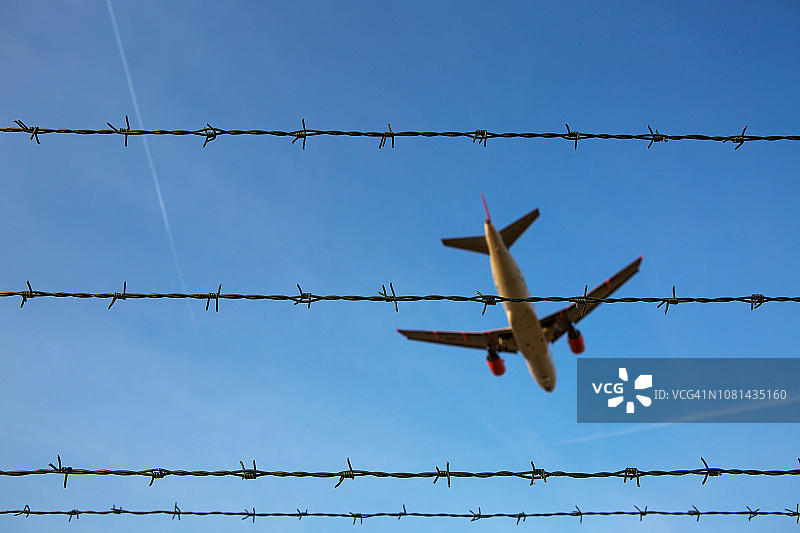 勃兰登堡舍内费尔德机场上空的带刺铁丝网和客机图片素材