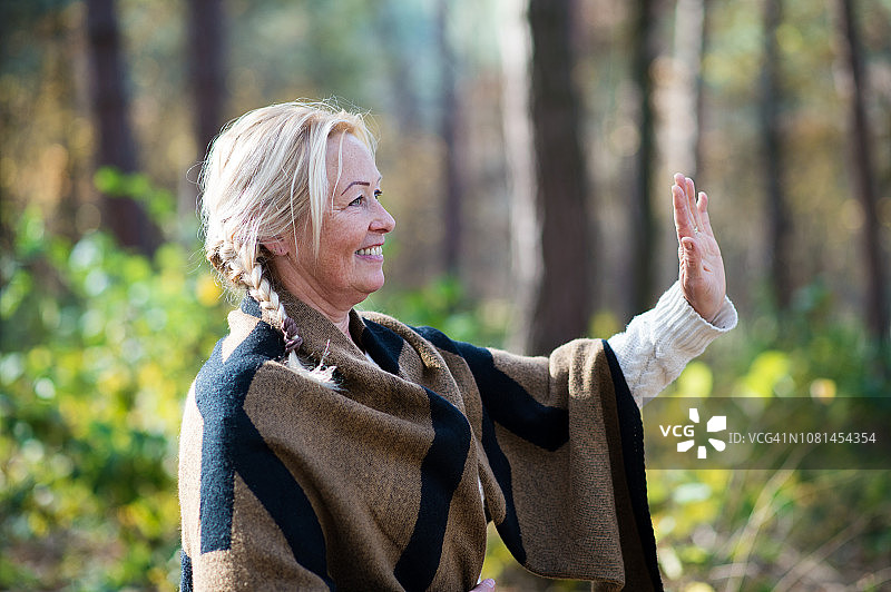 快乐的老年妇女站在秋天的户外挥手图片素材