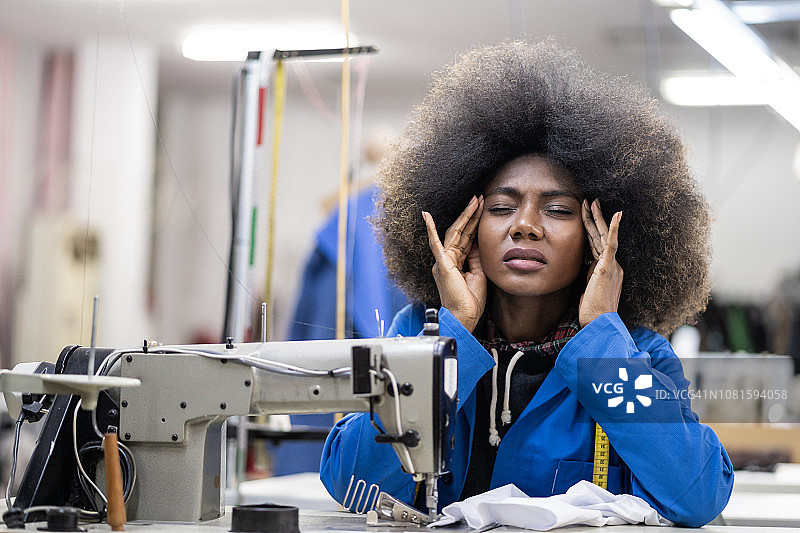 在时装工厂头痛的非洲工人图片素材