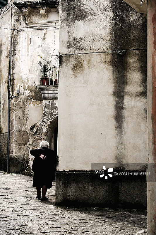 年长的女人在西西里小镇散步图片素材