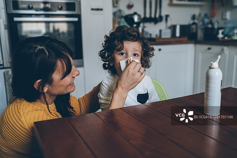 母亲帮助儿子擤鼻涕图片素材