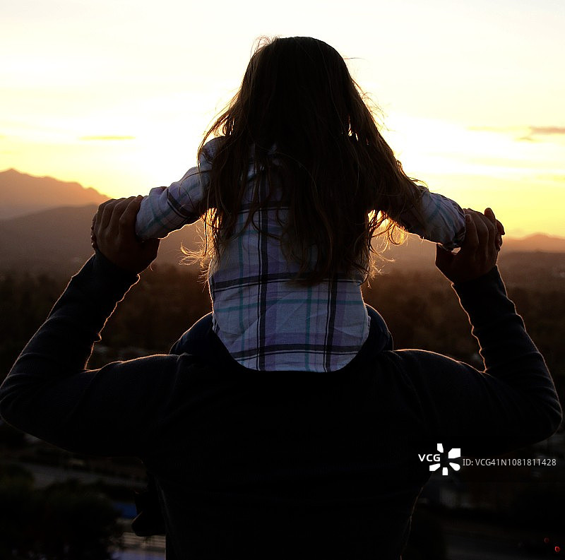 夕阳剪影：男人肩上的小女孩图片素材