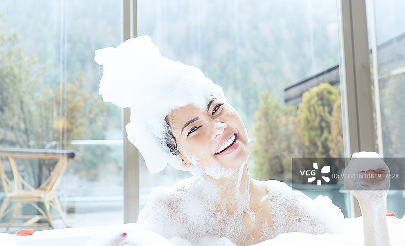 在豪华五星级酒店浴缸中淋浴并对着镜头微笑的亚洲女性肖像图片素材