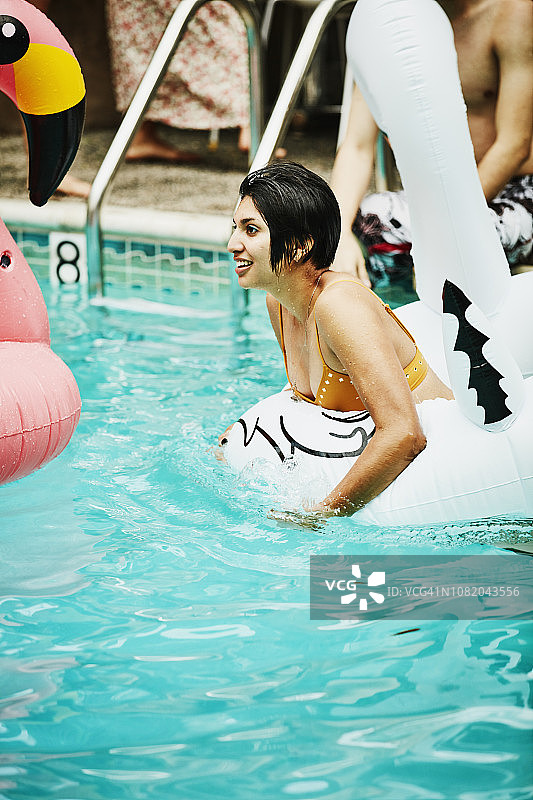 在酒店泳池派对上，于充气玩具中放松的女人图片素材