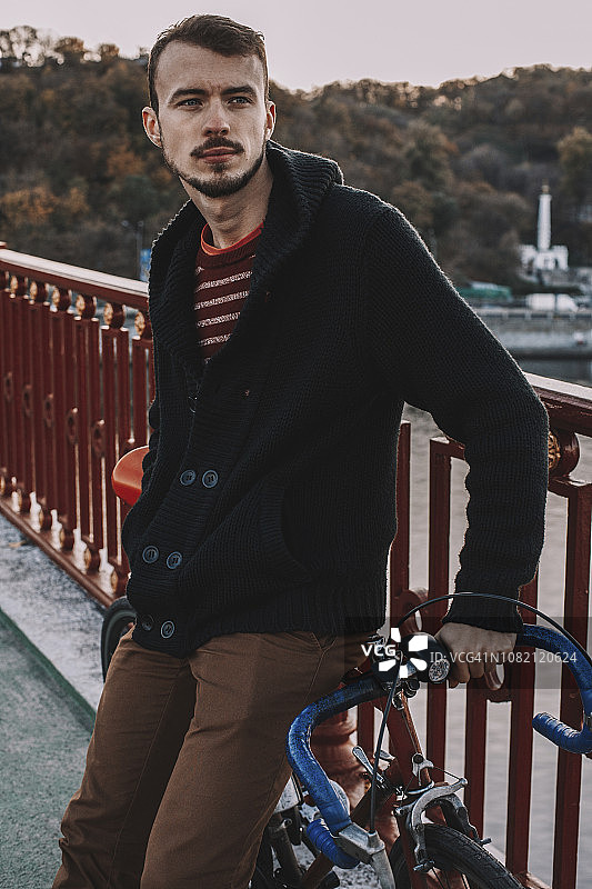 日落时分，站在桥上与自行车一起沉思的男子图片素材