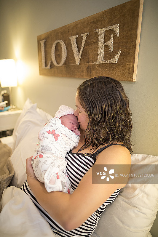 母亲在家中床上亲吻新生女儿图片素材