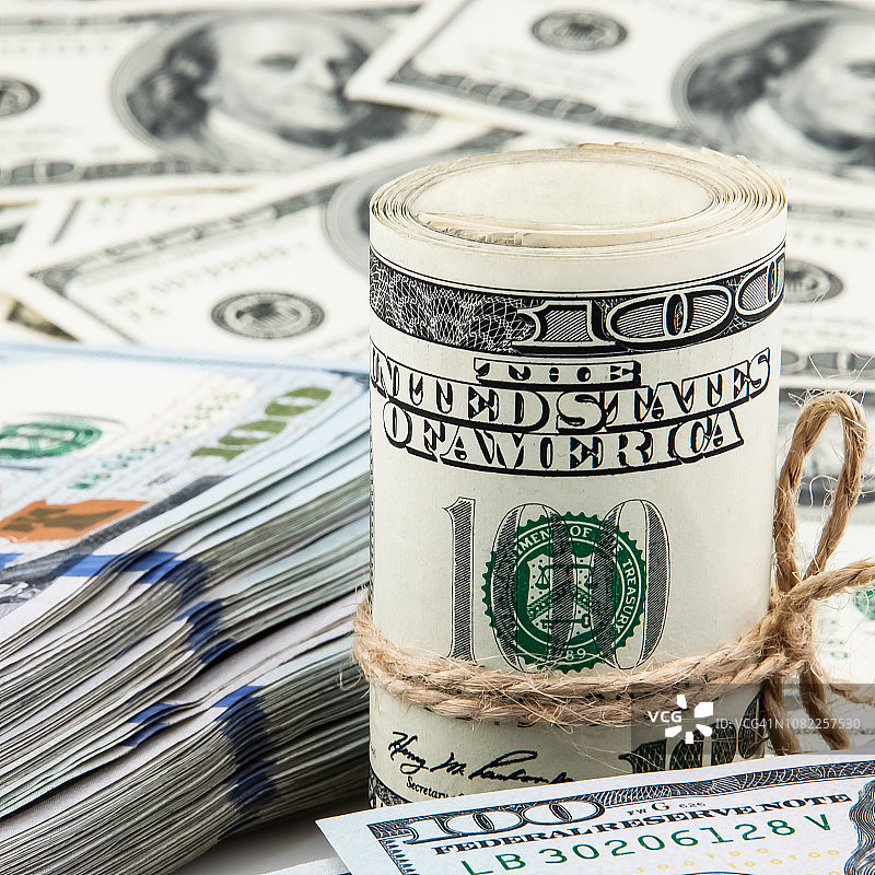 美元卷和一叠美元，背景是百元美钞图片素材