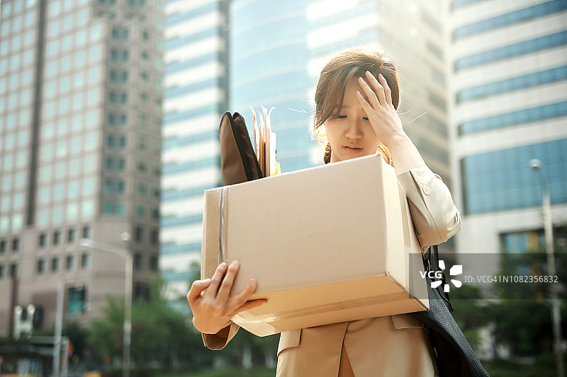 被解雇的女商人抱着装有个人物品的箱子图片素材