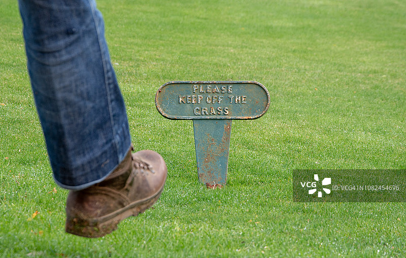 人物无视标志牌踩踏草坪图片素材