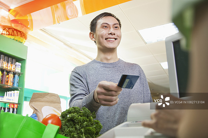 中国顾客在食品店用信用卡付款给收银员图片素材