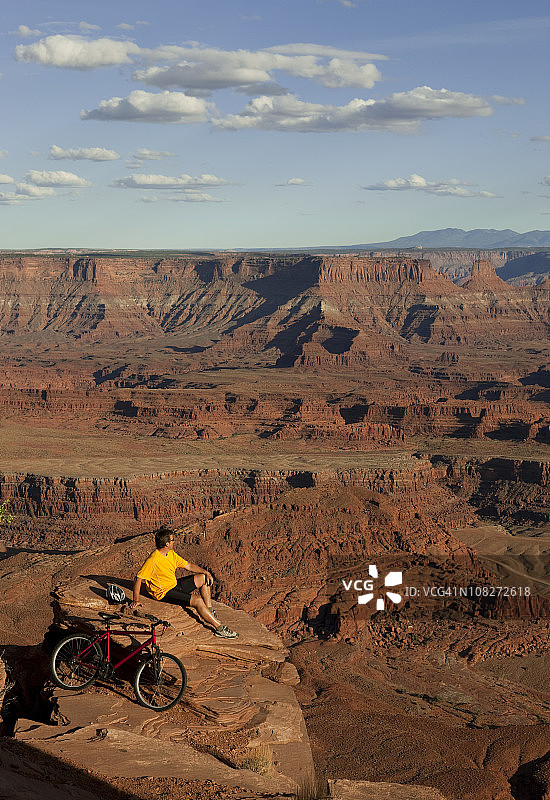 在犹他州摩押的岩石边缘看风景的男人图片素材