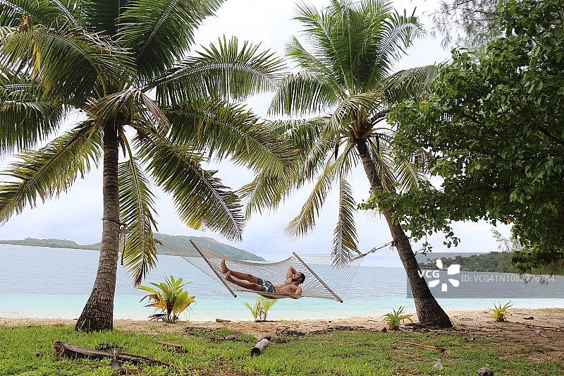一个年轻男人在斐济的吊床上放松图片素材