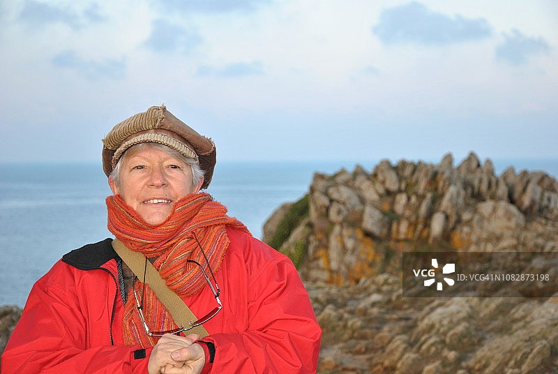 老年人在海边穿红色夹克戴棕帽图片素材