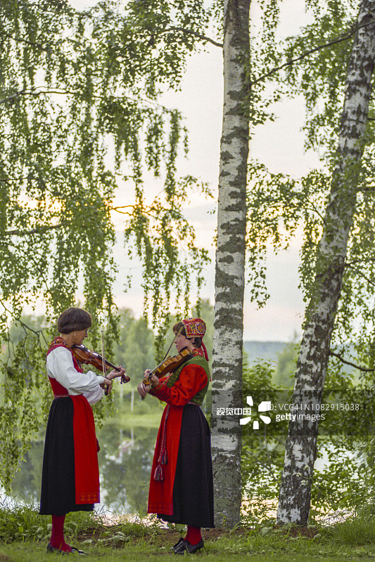 两个拉小提琴的女人穿着传统的达拉那服装图片素材