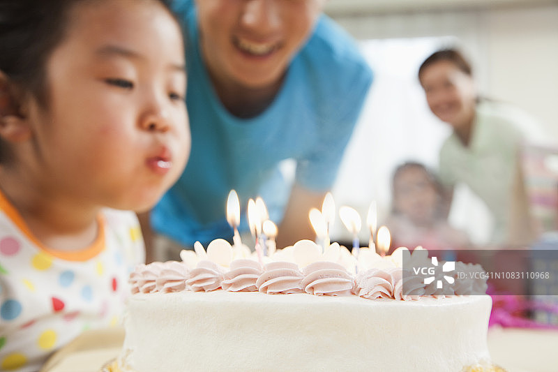 中国女孩吹灭生日蛋糕上的蜡烛图片素材