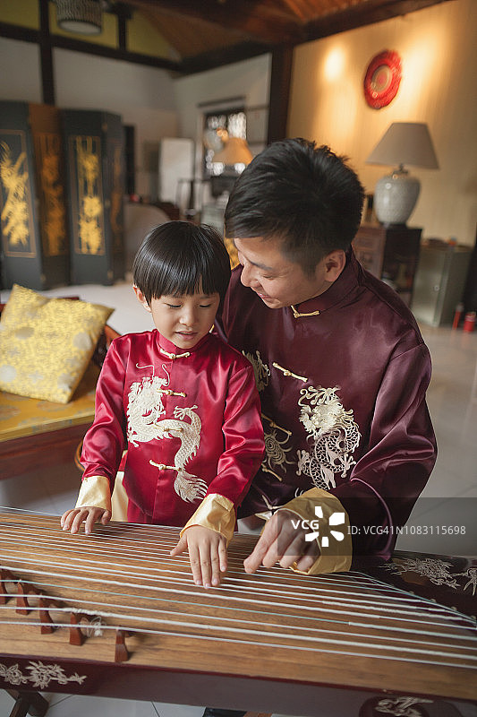 中国父子身穿传统服装弹奏竖琴图片素材