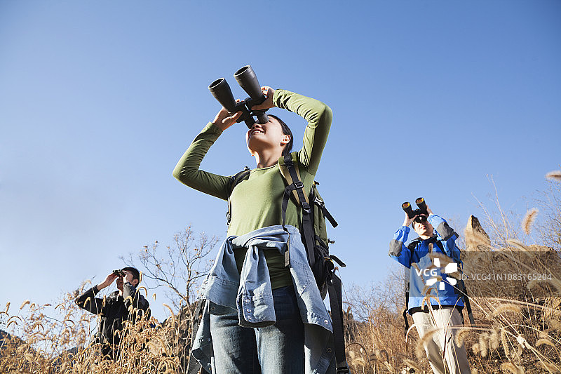在乡村景观中使用双筒望远镜的中国朋友图片素材