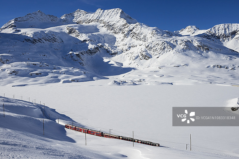 通往伯尼纳山口的列车，背景是结冰的湖泊和坎布雷纳峰，瑞士伯尼纳山脉图片素材