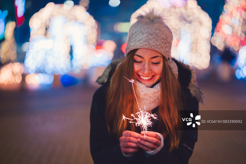 新年夜，快乐的女人拿着燃烧的烟花图片素材