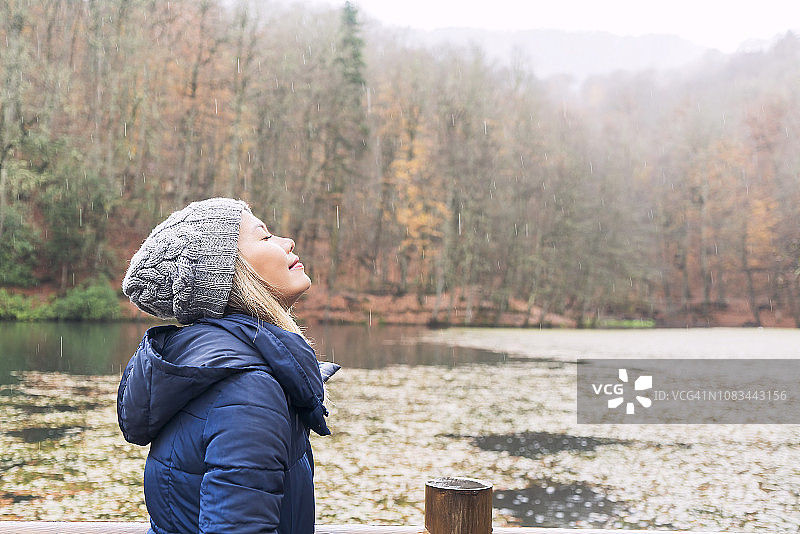 雨天里，女人在美丽的绿色湖泊上闻着空气图片素材