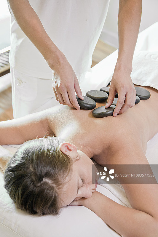女人在水疗中心享受热石按摩图片素材