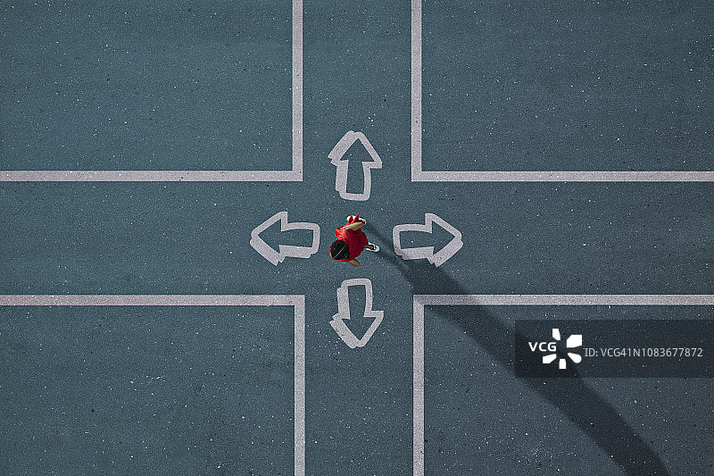 红衣女孩在彩绘十字路口选择方向图片素材