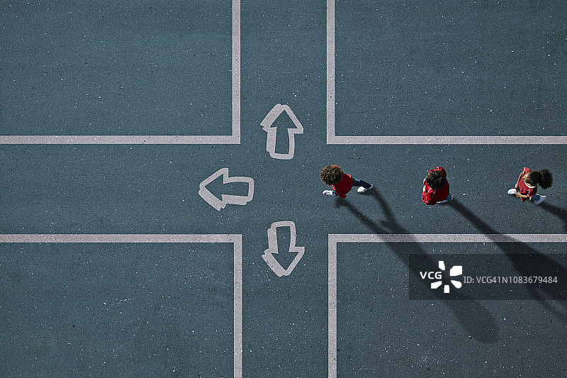 儿童穿着红色衣服走向绘有箭头的十字路口图片素材
