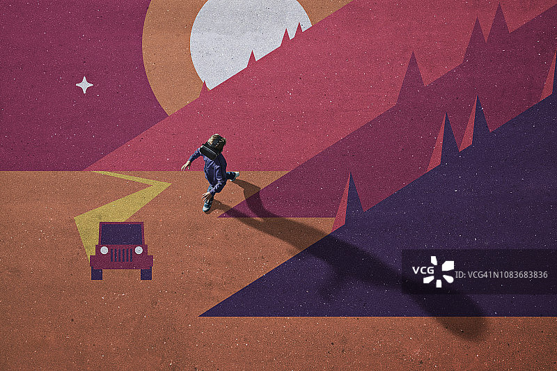 男孩戴着VR眼镜走在彩绘的假想山景中图片素材