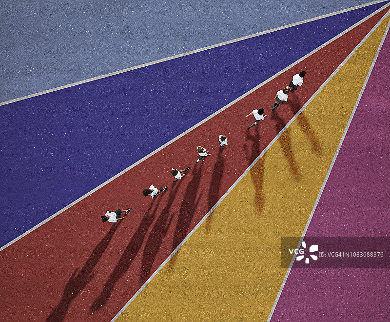 穿着制服的小学生在彩色背景上排队行走图片素材