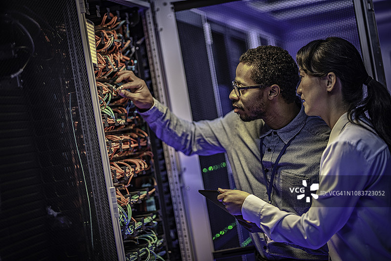 IT工程师调整数据中心服务器模块上的网络电缆连接图片素材