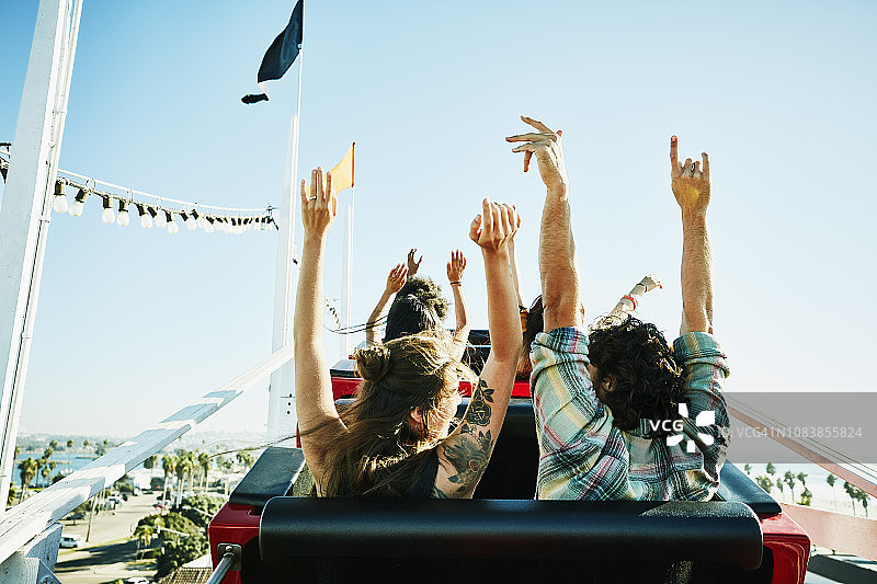 情侣在游乐园过山车上举起手臂，准备开始下降的背影图片素材