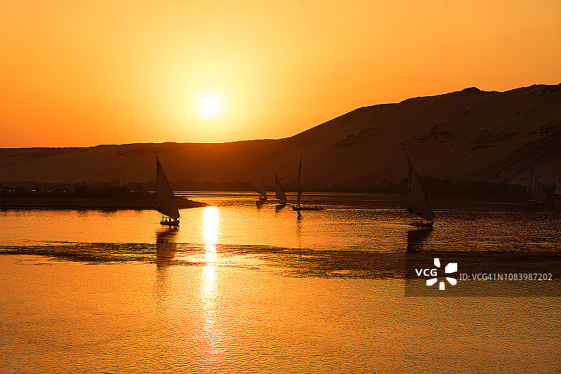 埃及卢克索尼罗河沿岸村庄传统船只的日落景观图片素材