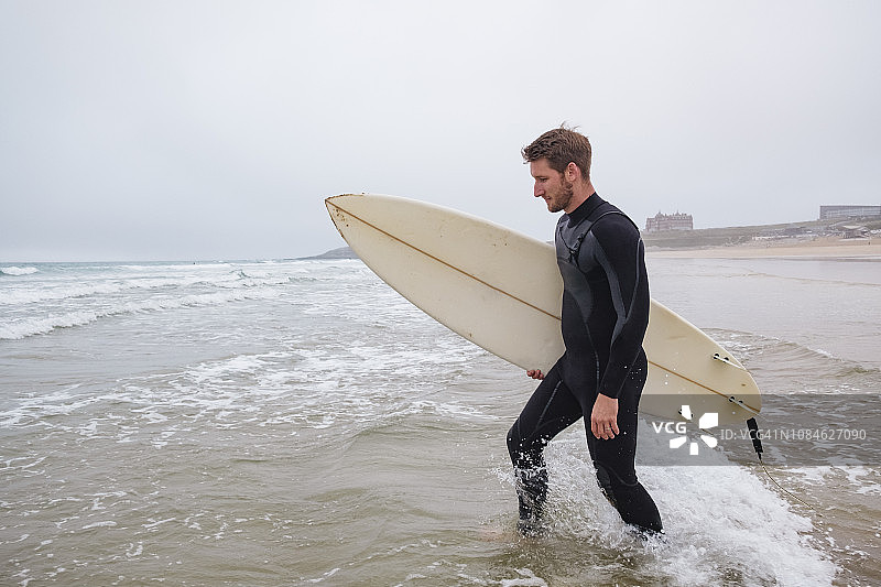 秋日，冲浪者在Fistral海滩入海准备冲浪图片素材