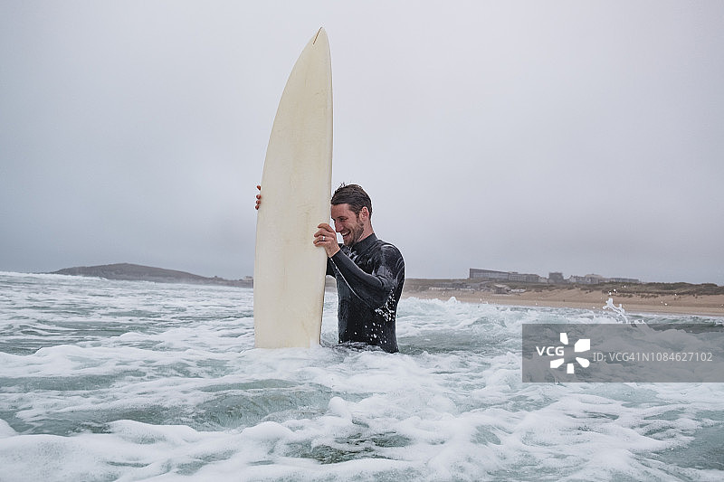 在秋季阴天，男冲浪者在康沃尔郡纽基 Fistral 海滩被海浪击中后大笑图片素材