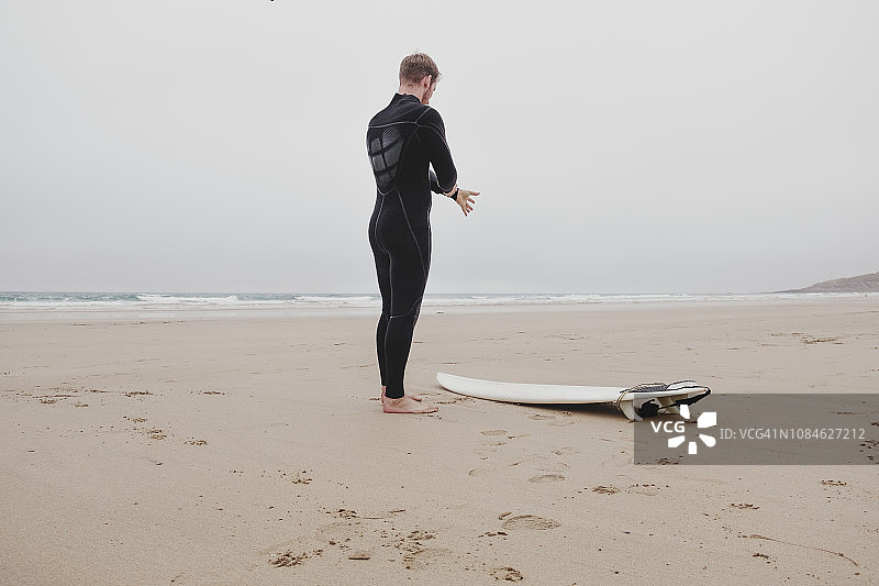 在康沃尔郡纽基 Fistral 海滩上穿着潜水服的男子图片素材