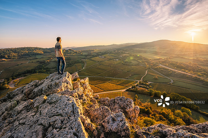 男人在勃艮第索吕特岩顶欣赏日落美景，法国图片素材