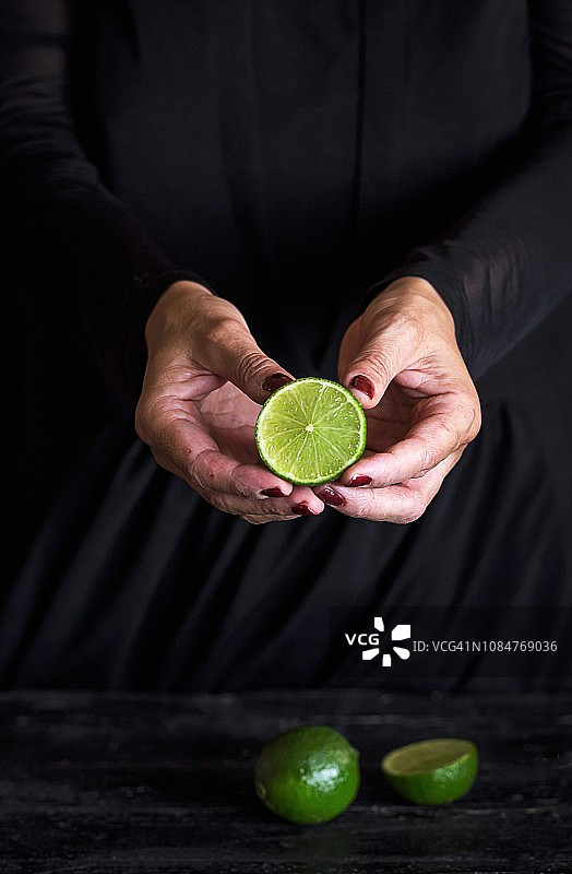 黑色背景上手持半个青柠的女人图片素材