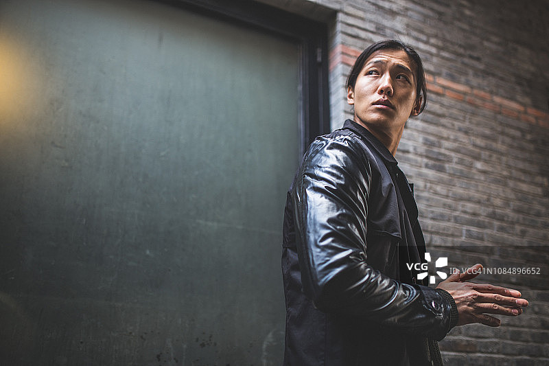 穿着皮夹克的亚洲男人回头看图片素材