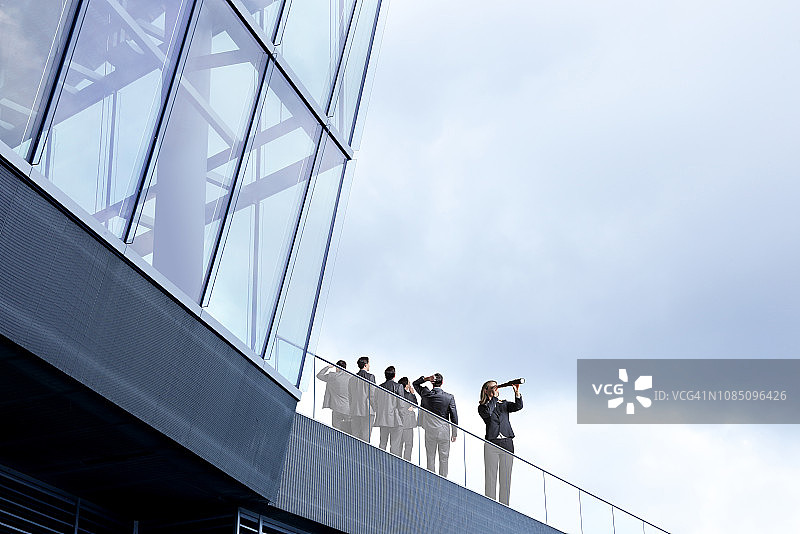 女商人用单筒望远镜观察，男商人朝相反方向看图片素材