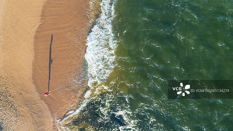 在乌拉圭埃斯特角海滩，一个男人在海边钓鱼，高角度视角，无人机视角，沙滩和海洋，正上方图片素材