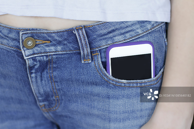 牛仔裤口袋里拿着智能手机的女人图片素材