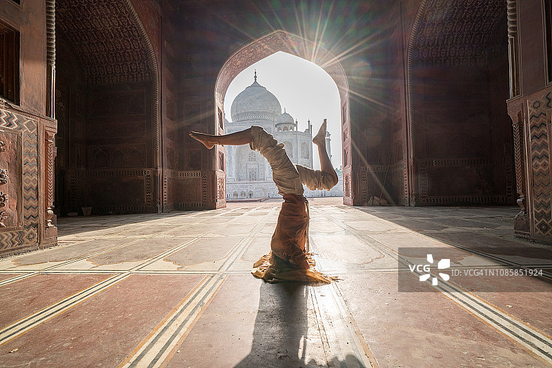 年轻女人在印度著名的泰姬陵日出时练习瑜伽——头倒立姿势图片素材