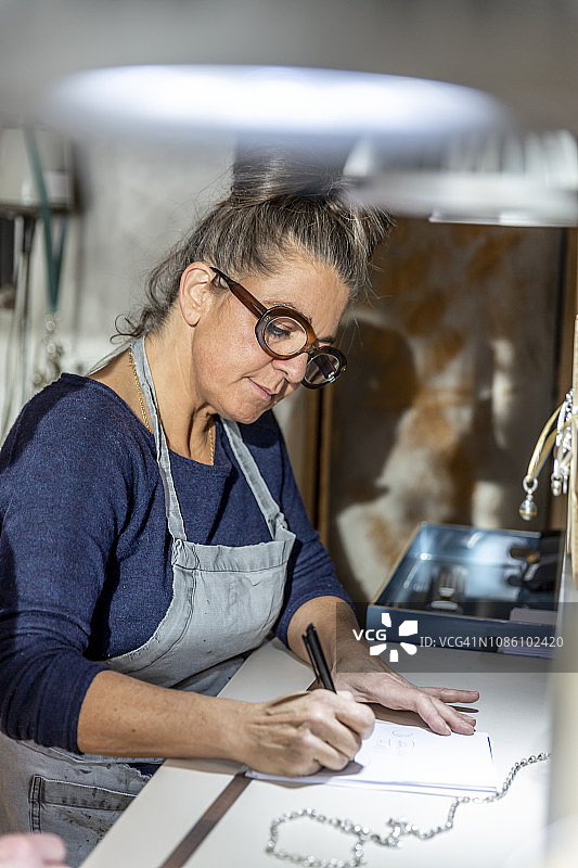 专注的金匠在她的工作室里做文书工作图片素材