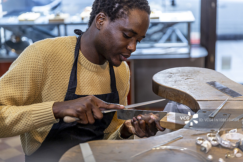 金匠在他的珠宝店/工作室里锉削图片素材