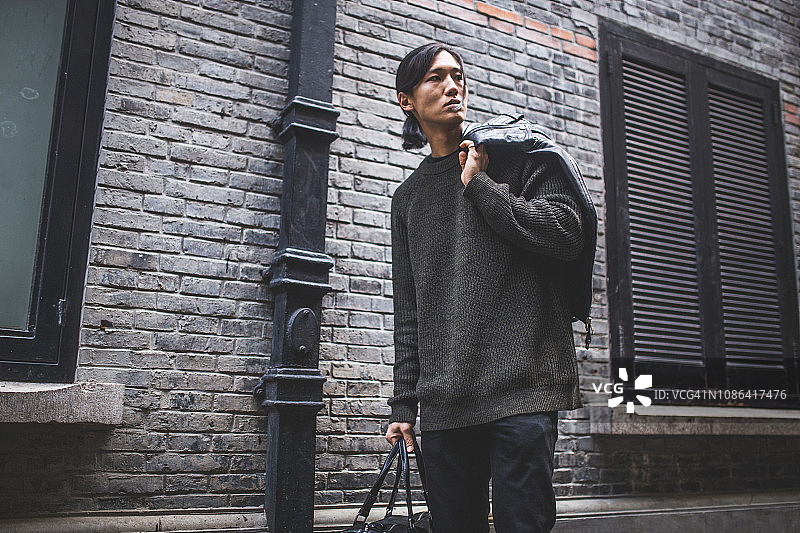 亚洲男人提着包走在街上图片素材