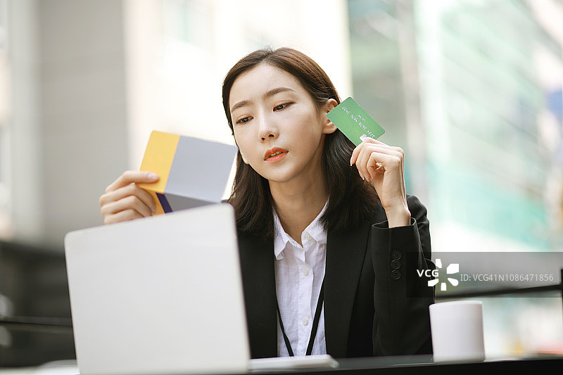 女商人在咖啡馆用信用卡和银行存折进行网上购物图片素材