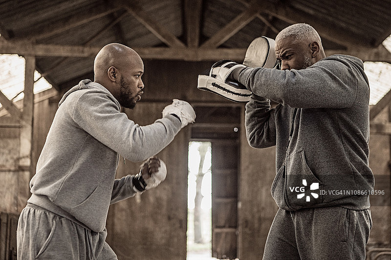 在废弃农场与教练一起锻炼的黑人拳击手图片素材