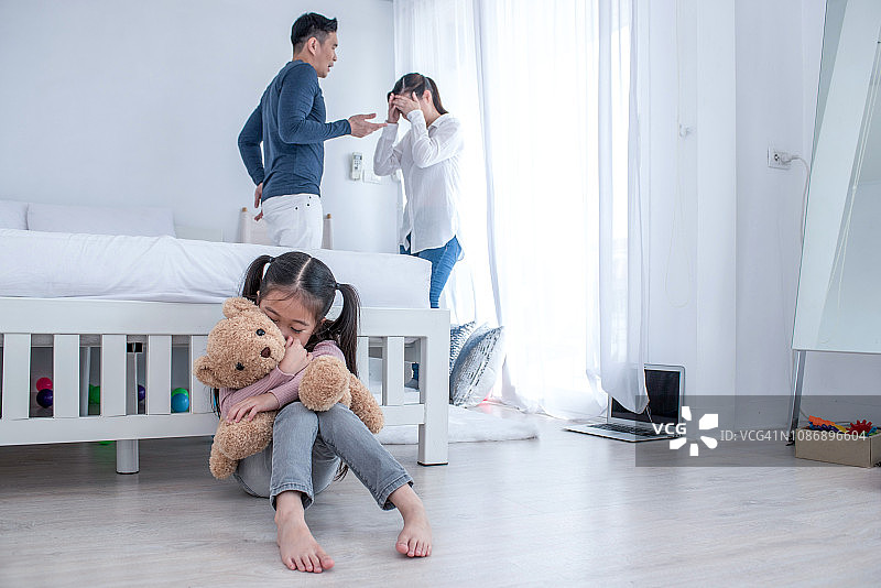 父母家庭争吵的概念：年轻夫妇在孩子面前争吵，孩子们对父母的争吵感到非常难过，孩子们正在哭泣和头痛图片素材